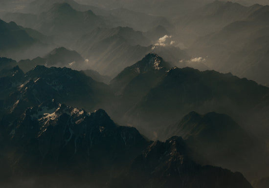 Birds view of a dark mountain scenery obscured by white mist.