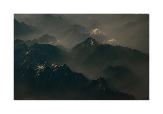 Birds view of a dark mountain scenery obscured by white mist.