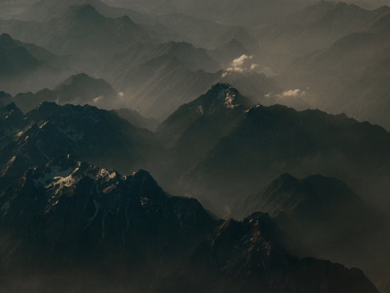 Birds view of a dark mountain scenery obscured by white mist.