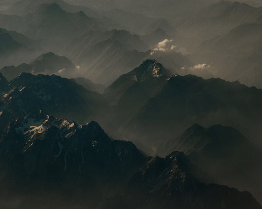 Birds view of a dark mountain scenery obscured by white mist.
