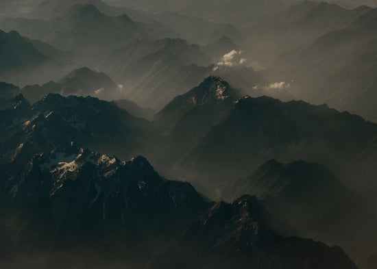 Birds view of a dark mountain scenery obscured by white mist.