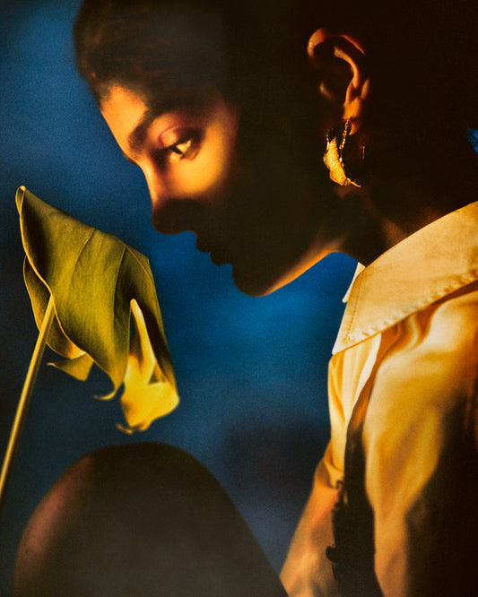 Woman staring into a leaf in front of a blue background.