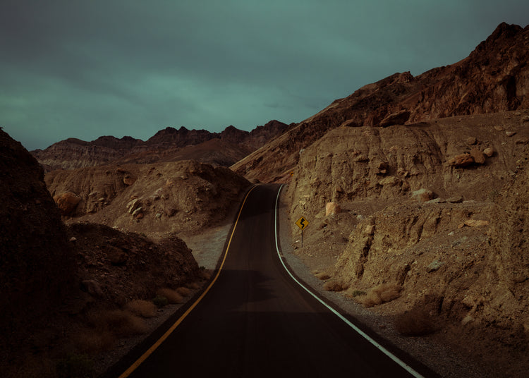 Asphalt road slithering its way through a rough mountain scenery.