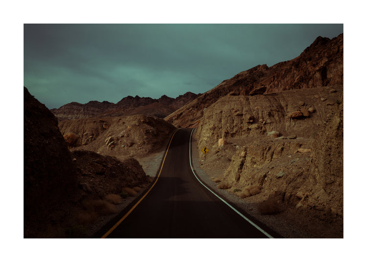 Asphalt road slithering its way through a rough mountain scenery.