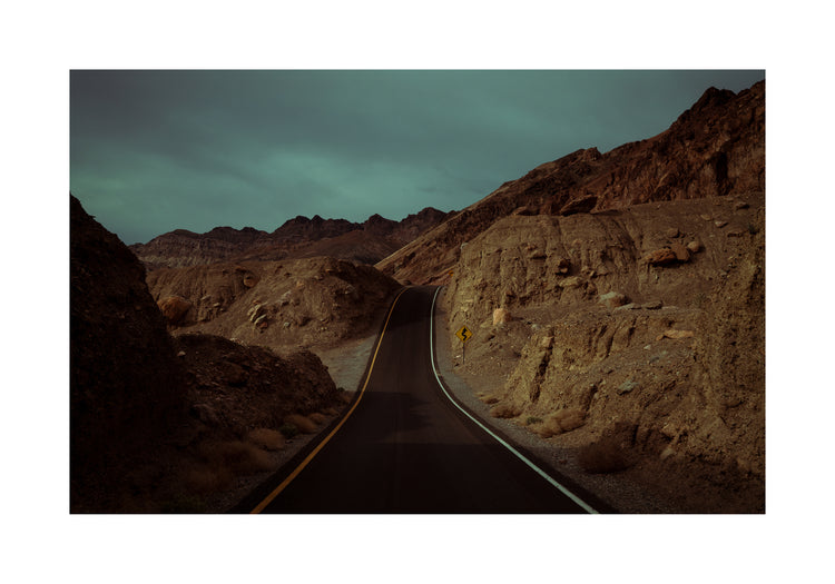 Asphalt road slithering its way through a rough mountain scenery.
