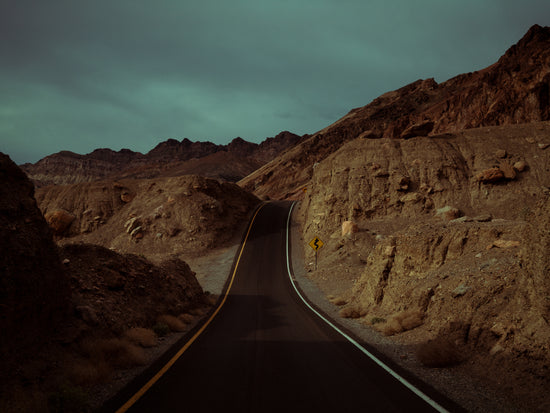 Asphalt road slithering its way through a rough mountain scenery.