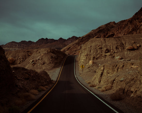 Asphalt road slithering its way through a rough mountain scenery.