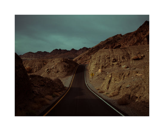 Asphalt road slithering its way through a rough mountain scenery.