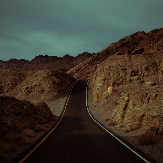 Asphalt road slithering its way through a rough mountain scenery.