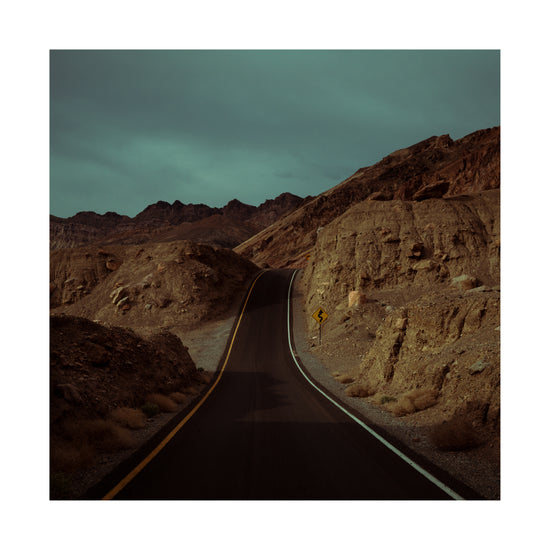 Asphalt road slithering its way through a rough mountain scenery.