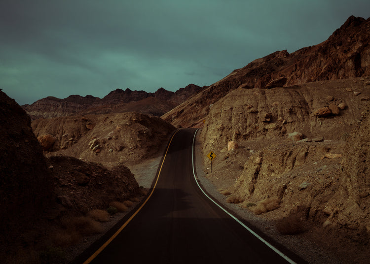 Asphalt road slithering its way through a rough mountain scenery.