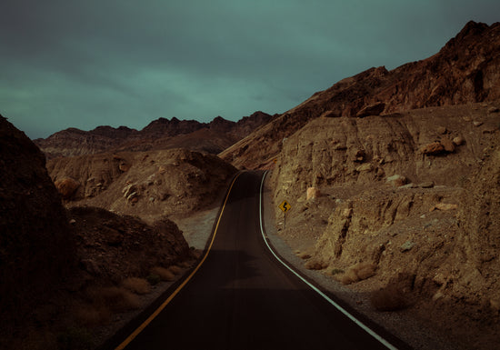 Asphalt road slithering its way through a rough mountain scenery.