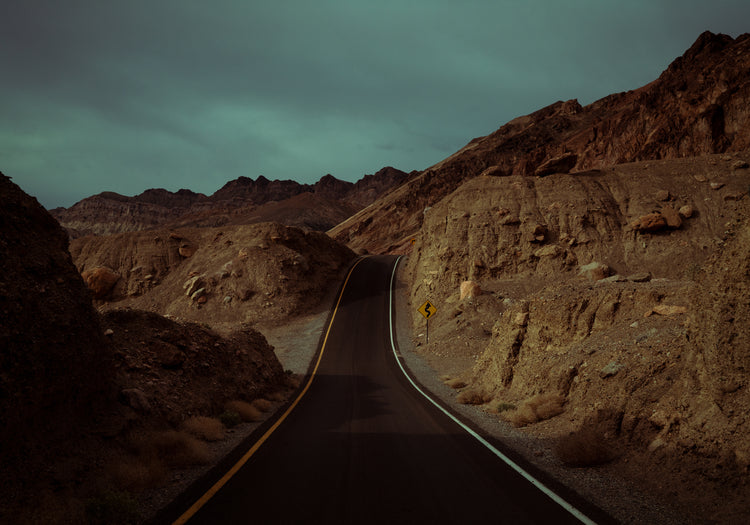 Asphalt road slithering its way through a rough mountain scenery.
