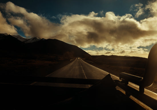 Road going through a landscape captured from the back of a car.