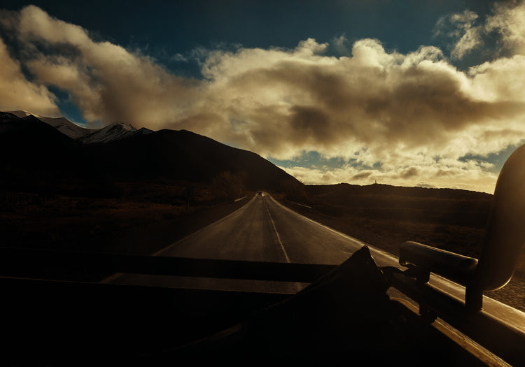 Road going through a landscape captured from the back of a car.