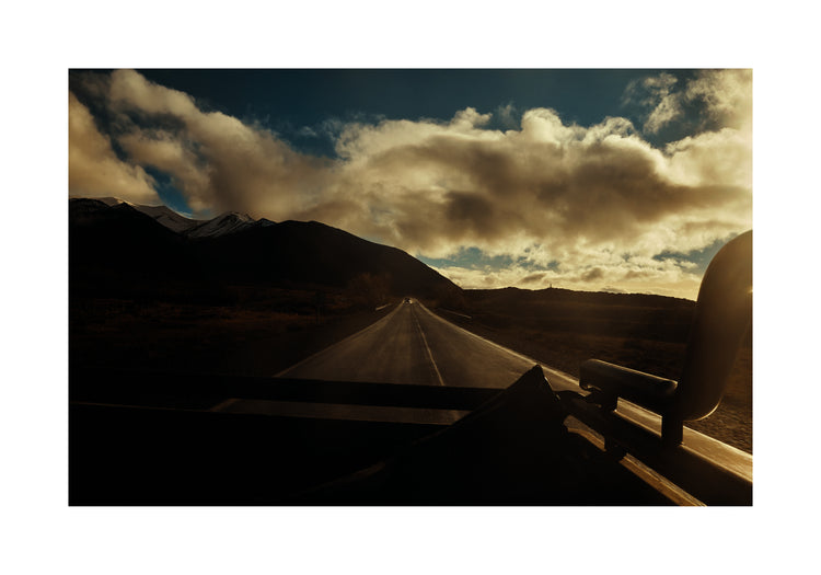 Road going through a landscape captured from the back of a car.