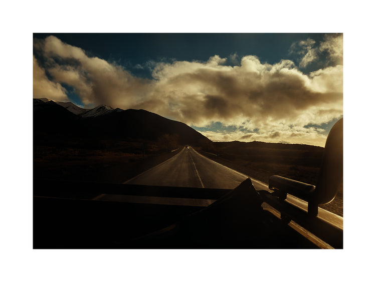 Road going through a landscape captured from the back of a car.