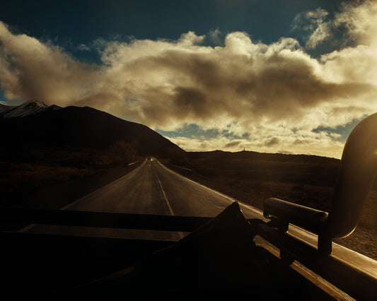 Road going through a landscape captured from the back of a car.