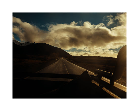 Road going through a landscape captured from the back of a car.