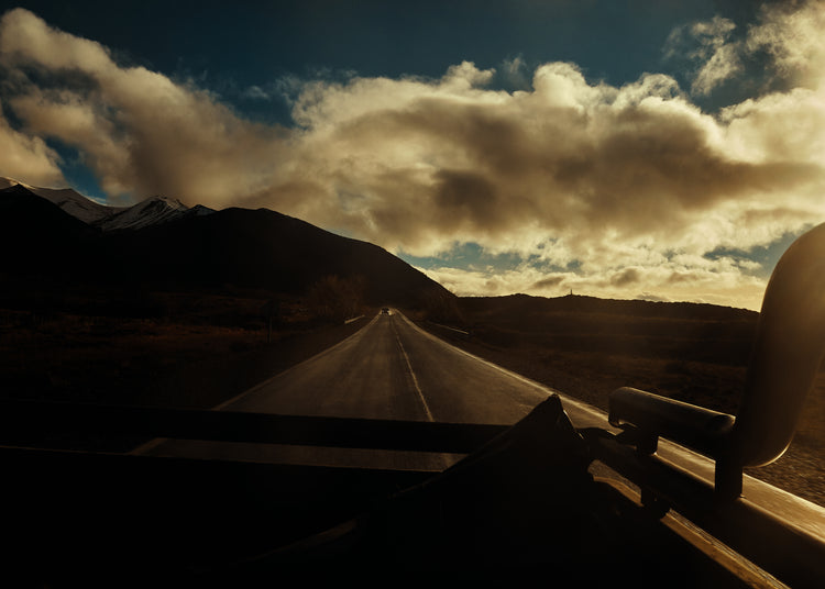 Road going through a landscape captured from the back of a car.