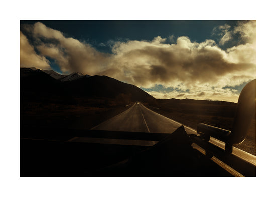 Road going through a landscape captured from the back of a car.