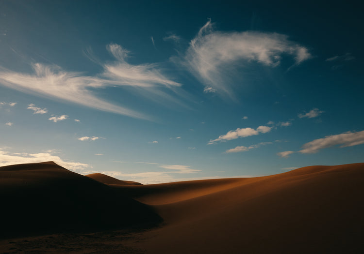 Dessert landscape with brown sand dunes under a clear blue sky.