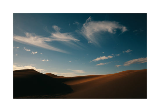 Dessert landscape with brown sand dunes under a clear blue sky.