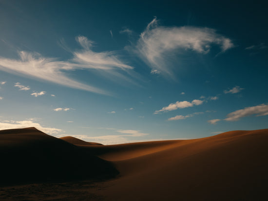 Dessert landscape with brown sand dunes under a clear blue sky.