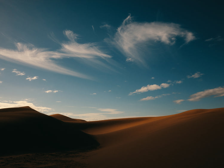 Dessert landscape with brown sand dunes under a clear blue sky.