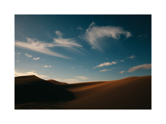 Dessert landscape with brown sand dunes under a clear blue sky.