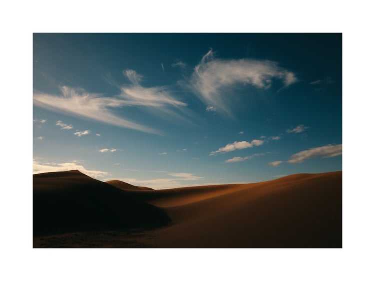 Dessert landscape with brown sand dunes under a clear blue sky.