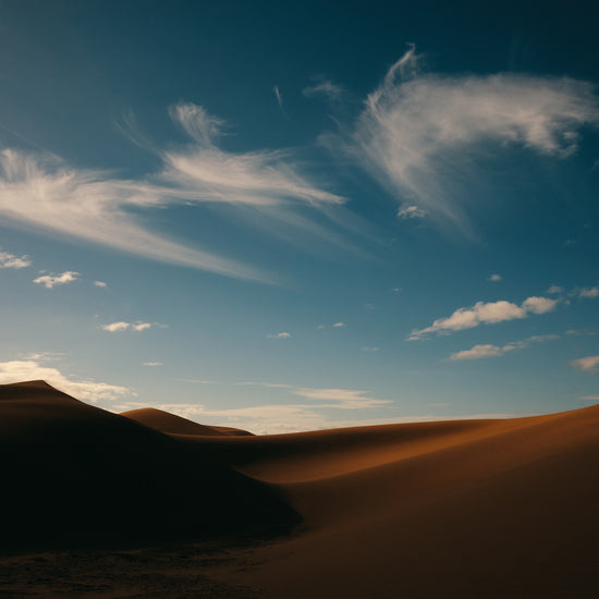 Dessert landscape with brown sand dunes under a clear blue sky.