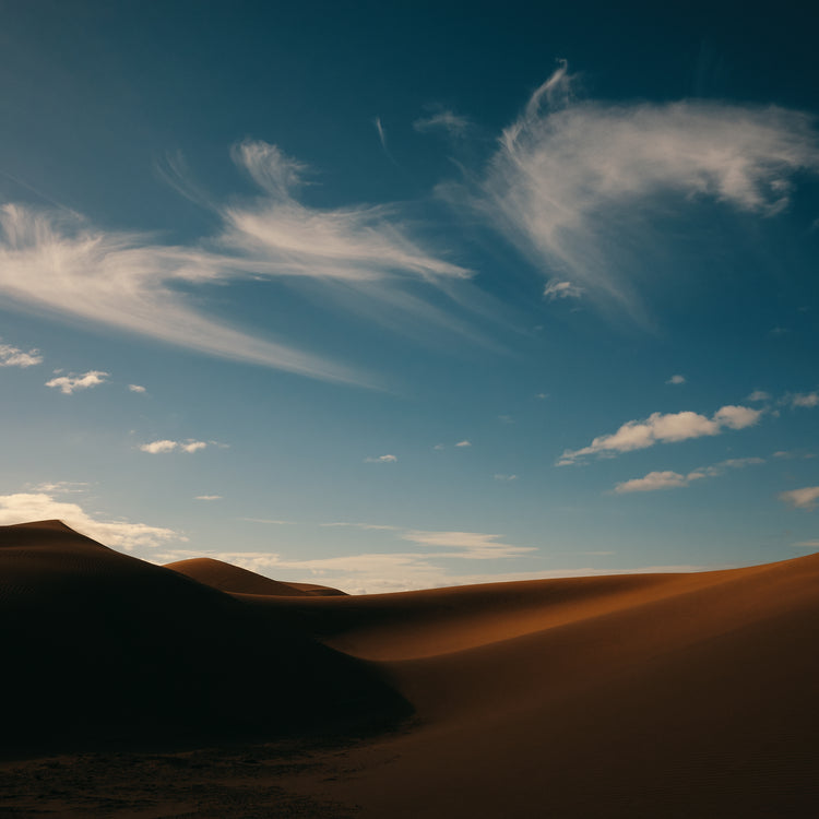 Dessert landscape with brown sand dunes under a clear blue sky.