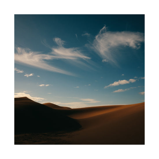 Dessert landscape with brown sand dunes under a clear blue sky.