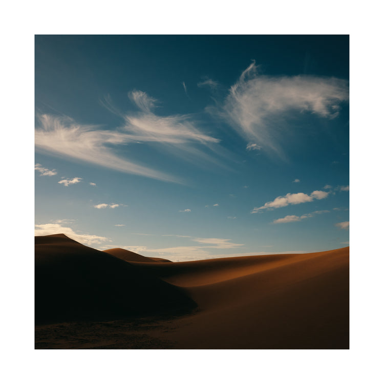 Dessert landscape with brown sand dunes under a clear blue sky.