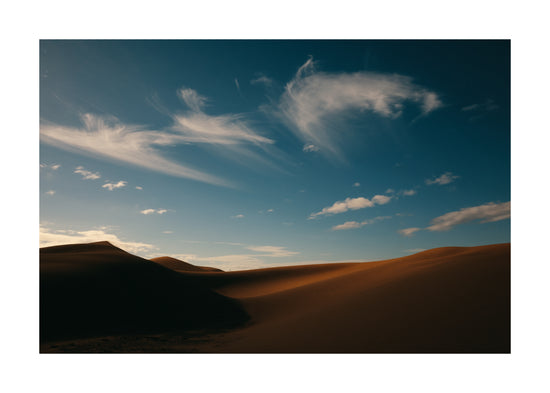Dessert landscape with brown sand dunes under a clear blue sky.