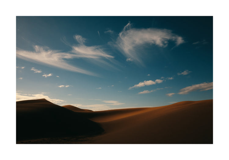 Dessert landscape with brown sand dunes under a clear blue sky.