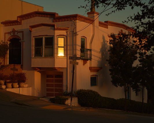 Suburban house laying at an intersection photographed during sunset.