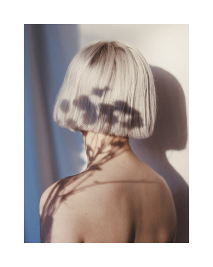 The back of a bare shouldered woman with a white page.