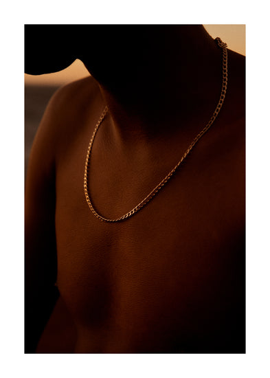 Bare chested man covered in goose bumps and wearing a gold chain necklace.