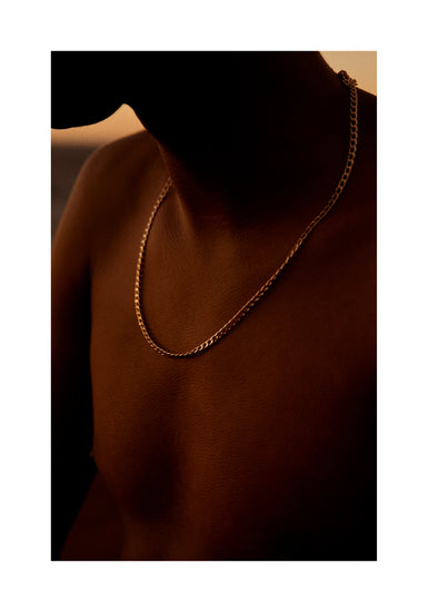 Bare chested man covered in goose bumps and wearing a gold chain necklace.
