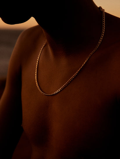 Bare chested man covered in goose bumps and wearing a gold chain necklace.