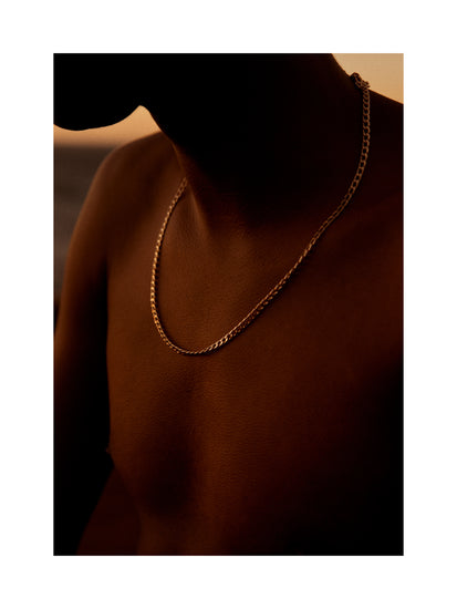 Bare chested man covered in goose bumps and wearing a gold chain necklace.