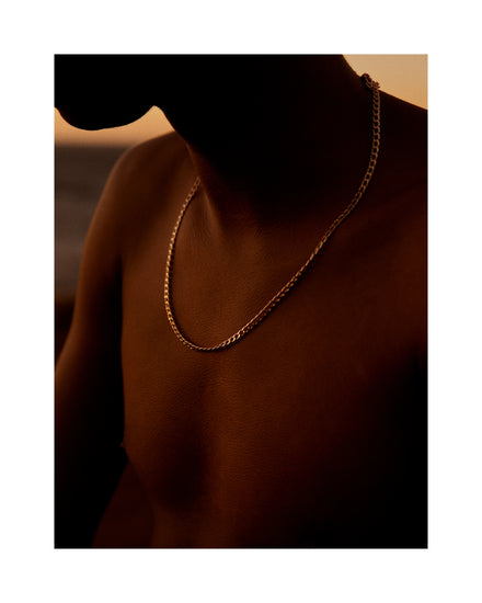 Bare chested man covered in goose bumps and wearing a gold chain necklace.