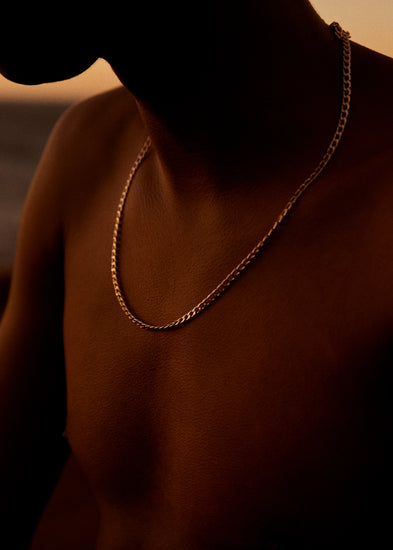 Bare chested man covered in goose bumps and wearing a gold chain necklace.