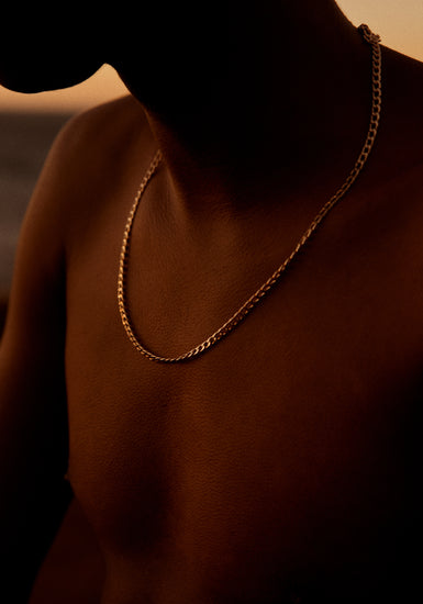 Bare chested man covered in goose bumps and wearing a gold chain necklace.