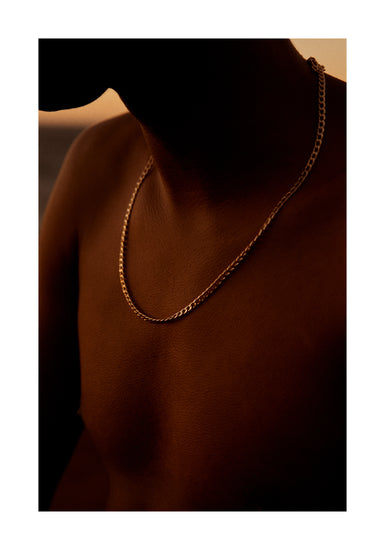 Bare chested man covered in goose bumps and wearing a gold chain necklace.