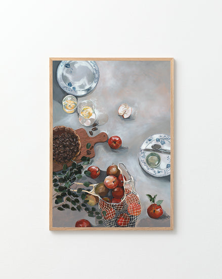 The How Do You Like These Apples Poster showcases a still life scene with red apples, a basket, plates, a cutting board, herbs, a cracked egg, and nuts on a gray tabletop for warm decor and rustic coziness.