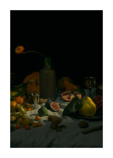 Still life photograph of fruits and flowers on a white canvas.