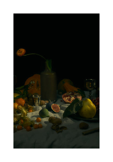 Still life photograph of fruits and flowers on a white canvas.